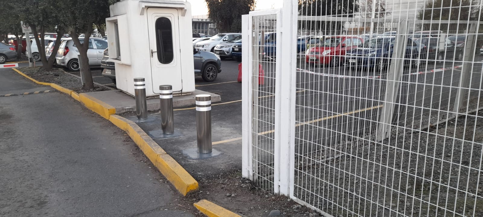 Bolardos de acero inoxidable con cintas reflectantes instalados junto a un acceso